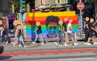 Close up of the mural "Standing with Dunja Hayali" by LAPIZ street art with people passing by